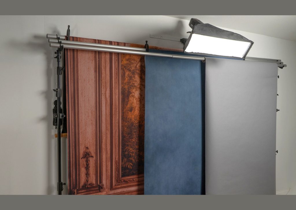 Professional photography studio with multiple mounted canvas backdrops and standfree lighting system creating an organized shooting space.